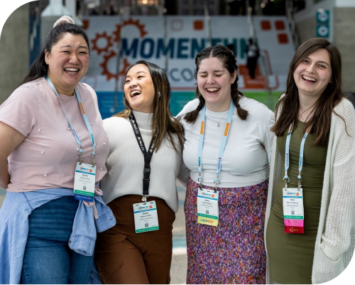 A group of NatCon attendees laugh while standing in front of the convention center.